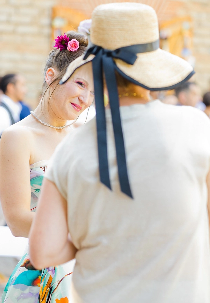 Regard doux de la mari&eacute;e &agrave; travers le chapeau d'une invit&eacute;