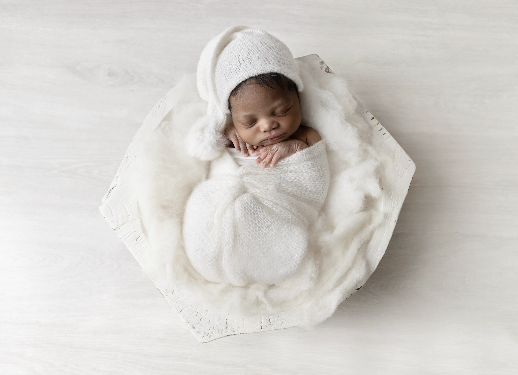 Photo d'un nouveau n&eacute; artistique dans un bol comme dans un cocon lors d'une s&eacute;ance naissance au studio de Tiana Photographe