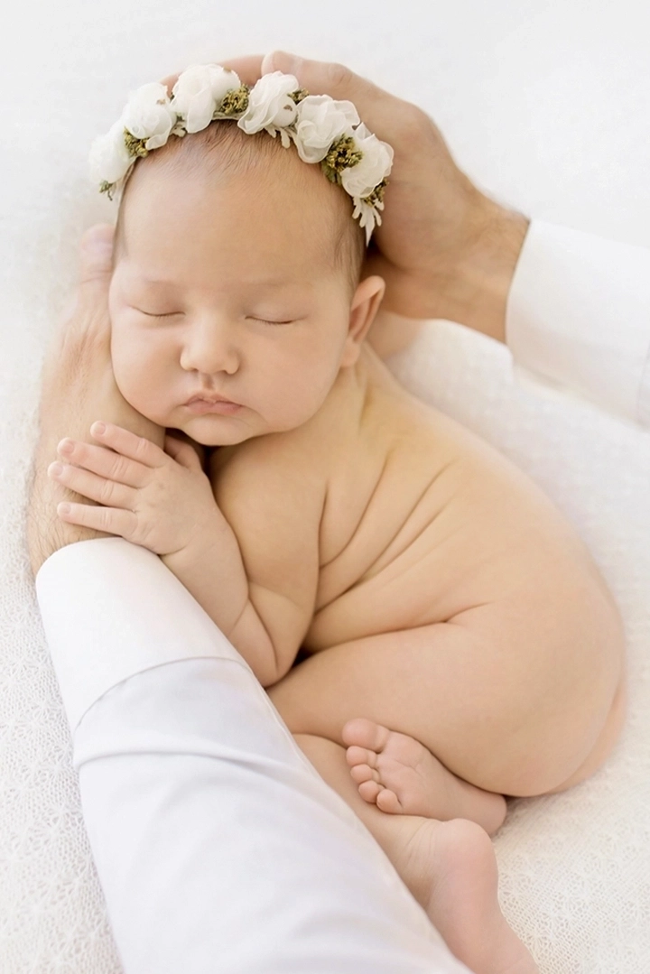 Photographie d'un nouveau n&eacute; dans les bras de son papa lors d'une s&eacute;ance nouveau n&eacute; avec Tiana Photographe Toulouse