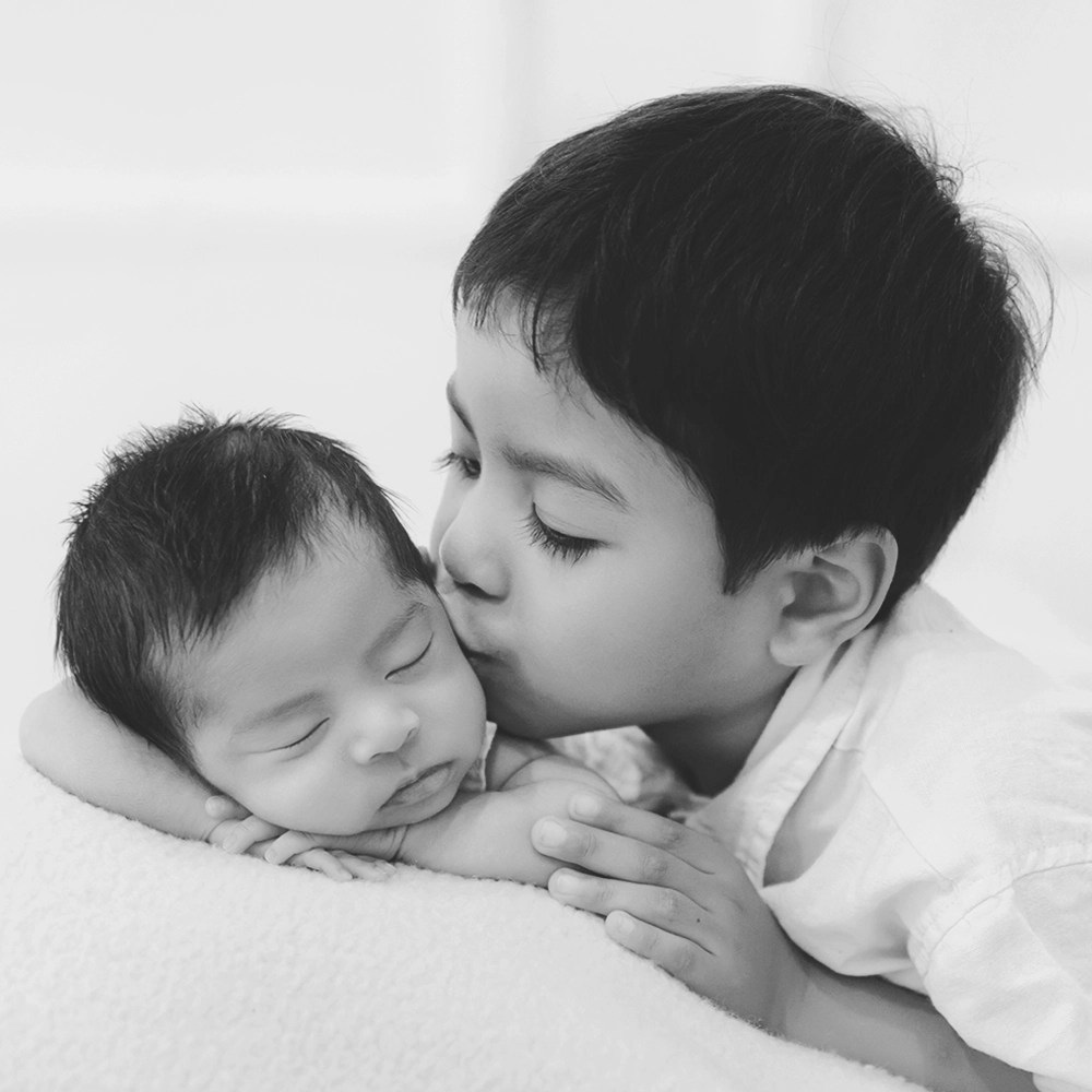 Photo d'un fr&egrave;re ain&eacute; qui embrasse son petit fr&egrave;re lors d'une s&eacute;ance photo avec Tiana Photographe Toulouse