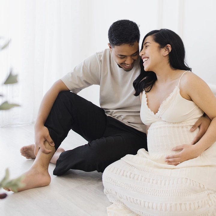 Photographie d'un couple heureux assise sur le sol dans le studio de Tiana Photographe Toulouse