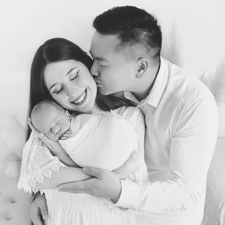 Photo d'un papa qui embrasse la maman lors d'une s&eacute;ance photo b&eacute;b&eacute;