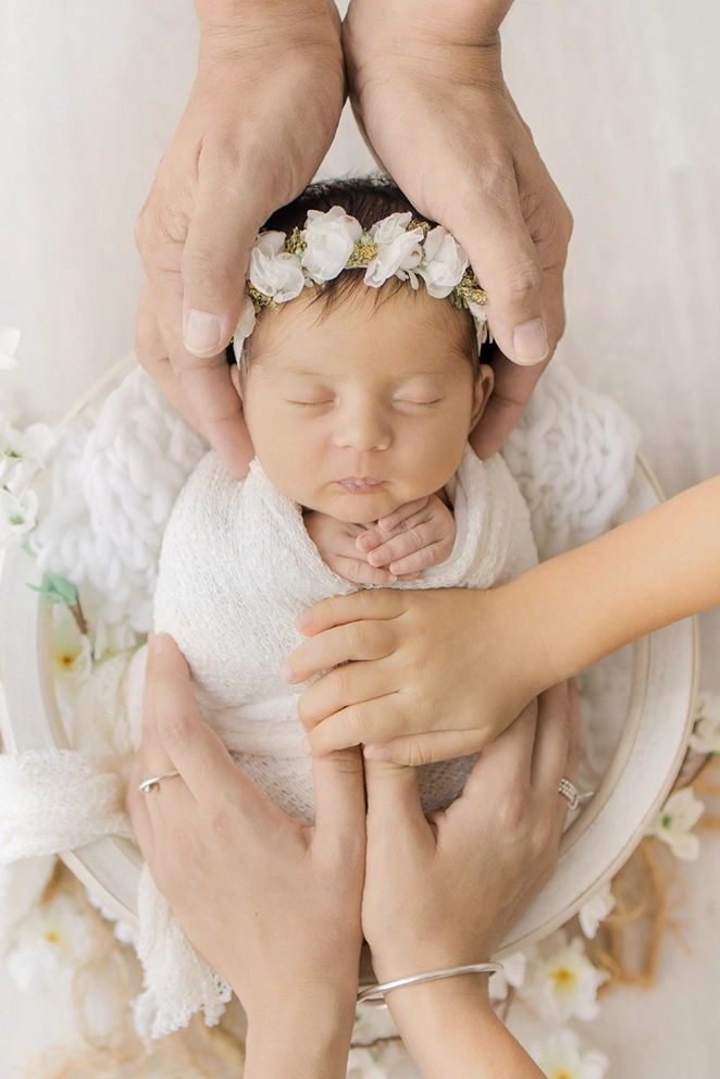Photographie artistique de nouveau n&eacute; avec les mains protecteur de sa famille lors d'un shooting naissance avec Tiana Photographe Toulouse